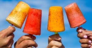 four hands holding different flavor popsicles from the 90s